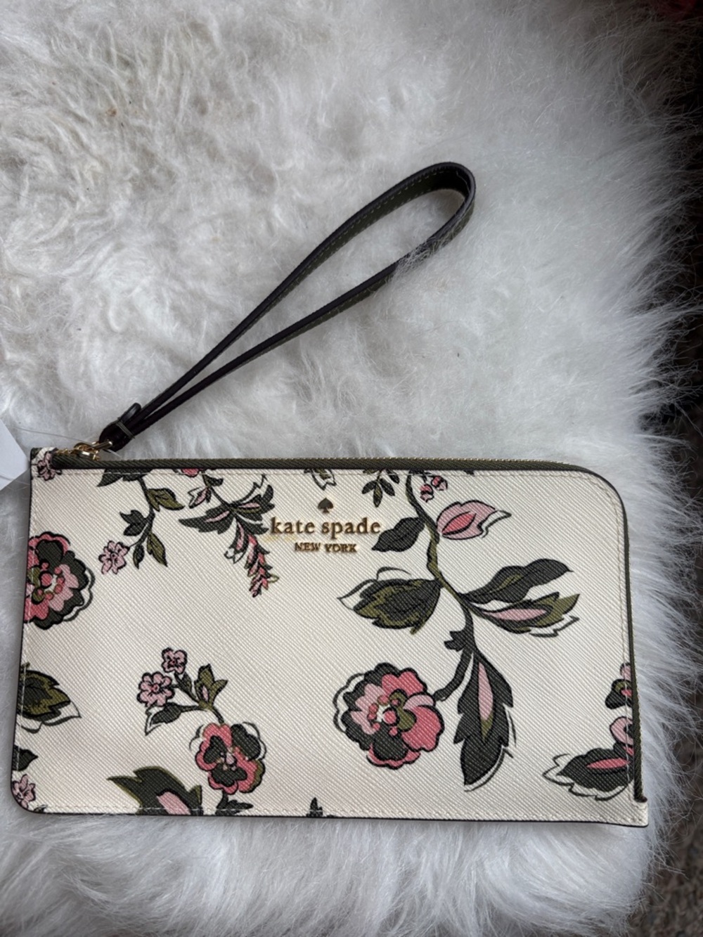 Kate spade cream floral wristlet with pink and green accents and black strap.